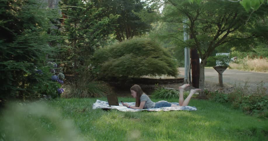 A girl lying in the garden using her cell phone