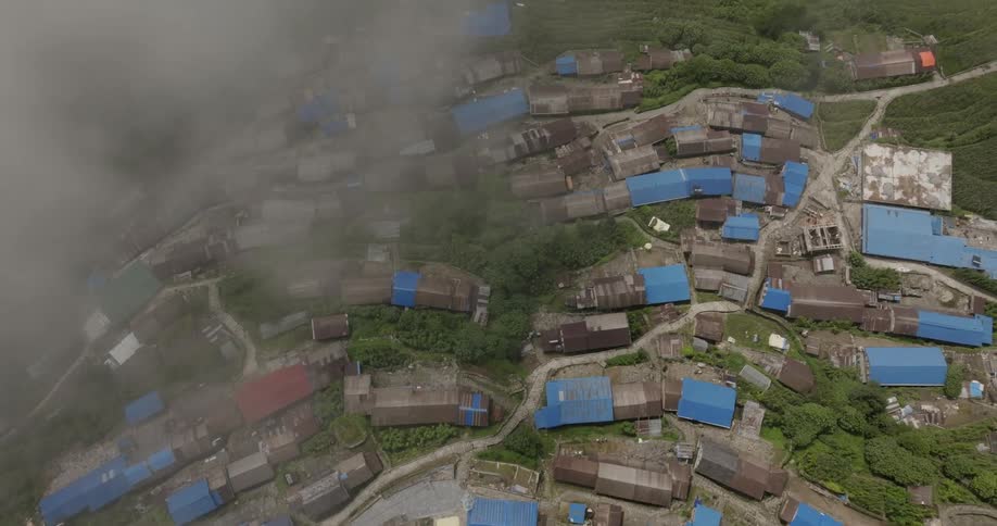 An aerial view of a rural village where buildings have blue roofs