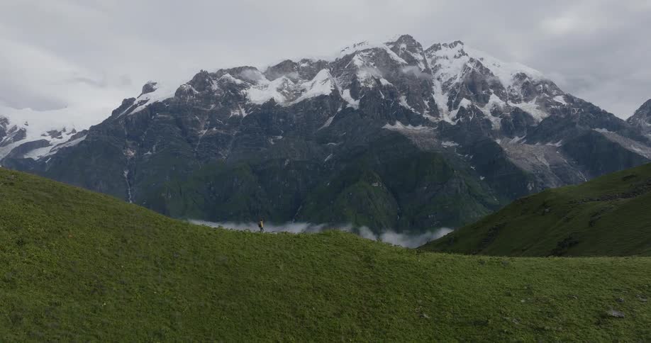 A person walking on top of the mountain during cloudy day