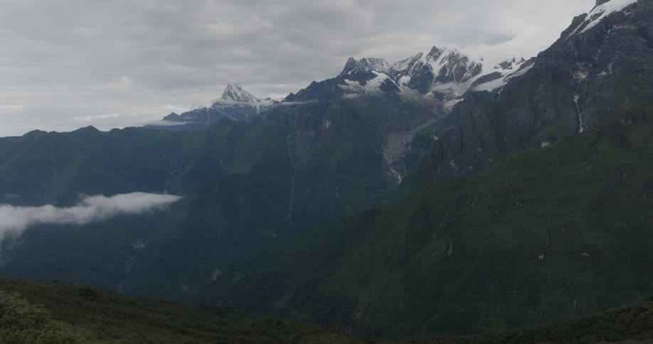 A snow capped mountain ridge under a cloudy sky during the day