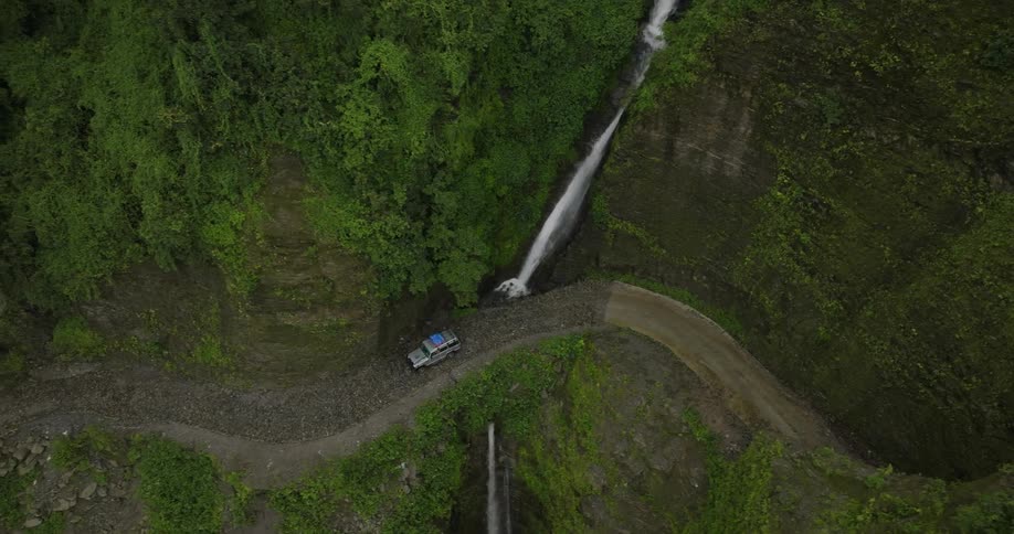 A car driving along a road that passes over a stream
