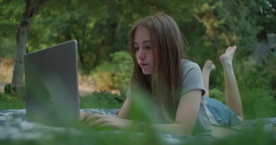 A girl is typing on a laptop in the garden