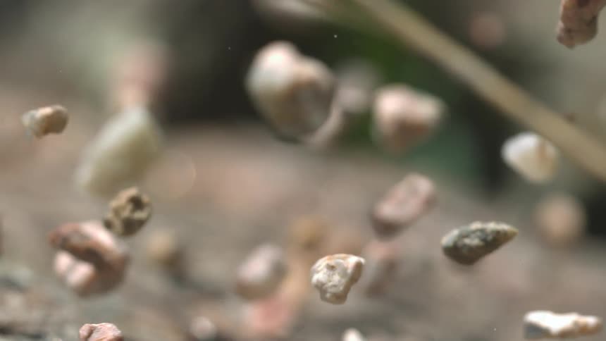 Stones and a few sticks but mostly stones are spinning and rotating as they are tumbling through the air