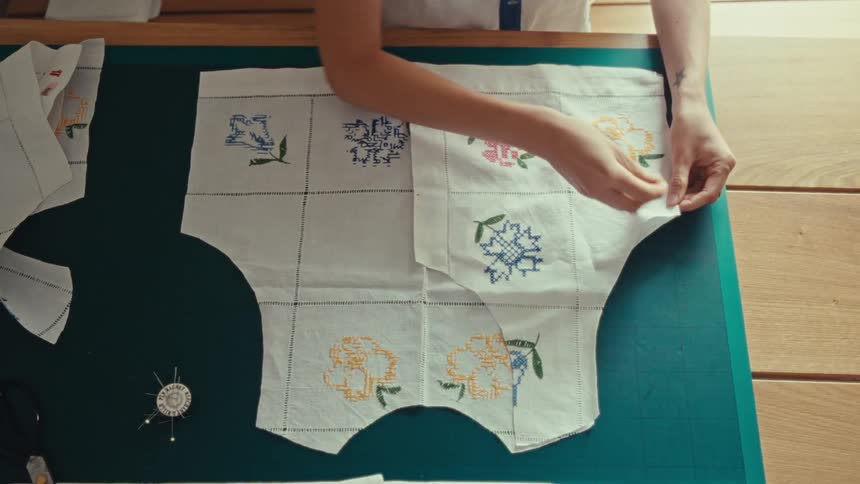 Hands of a woman inserting a needle into a fabric apron