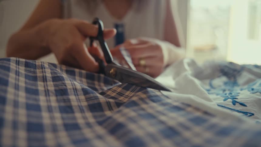 Human hands cutting a fabric using scissors