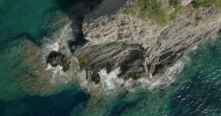 Waves crash against the base of seaside cliff