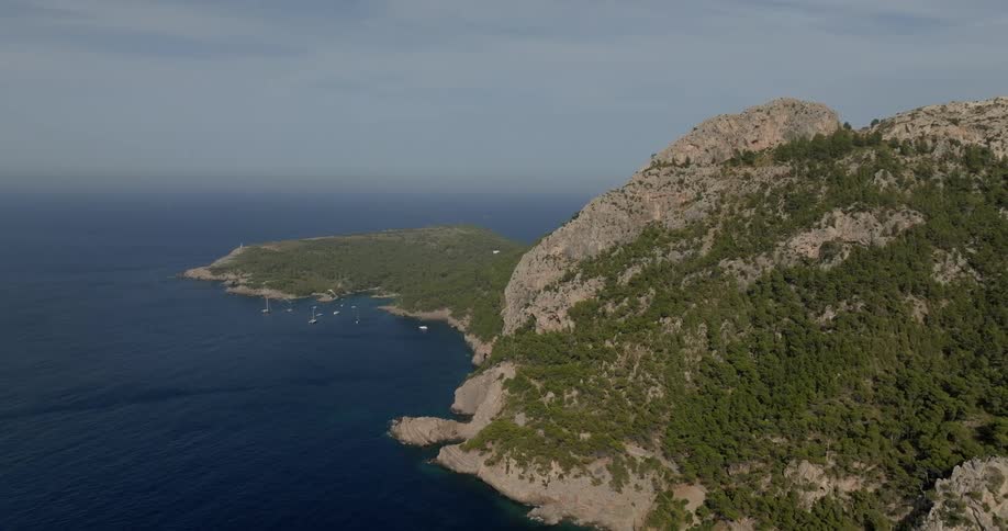 Aerial of a mountainous island with yachts anchored off the coast