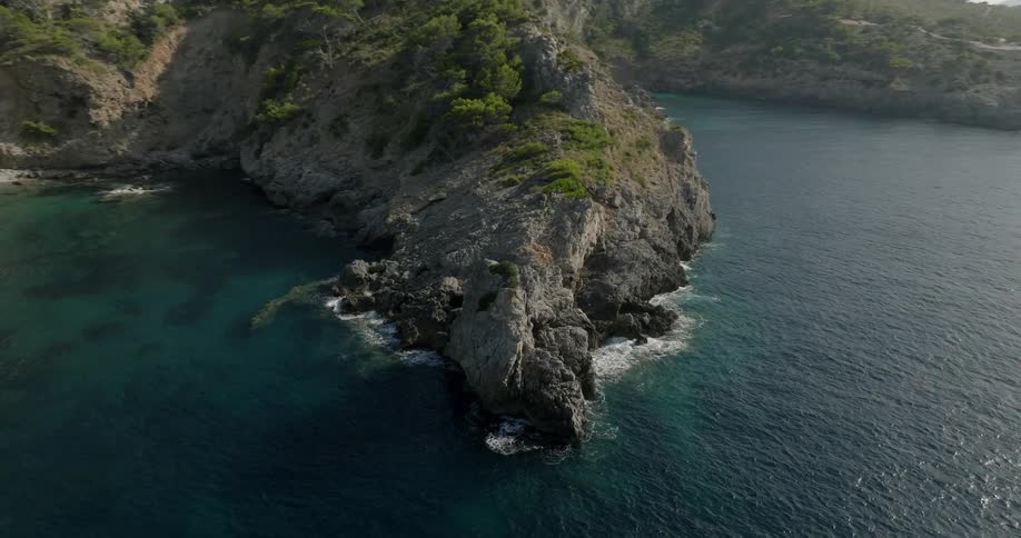 Aerial view of the rocky coastline next to the turquoise blue sea