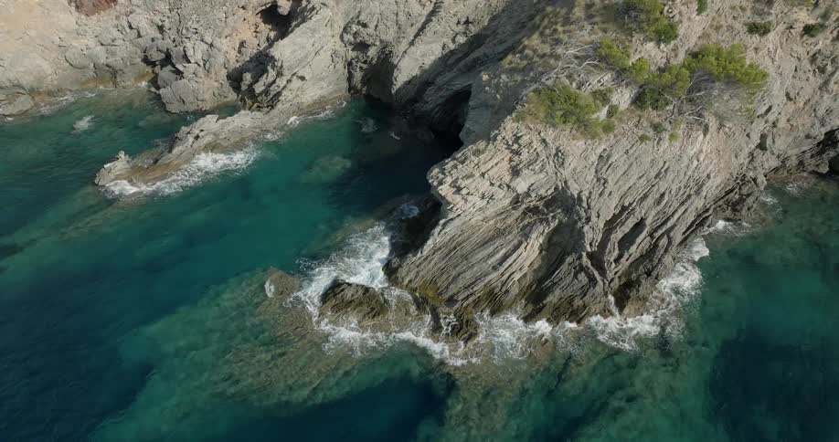 A coast of a mountain of rocks where the waves break and foam