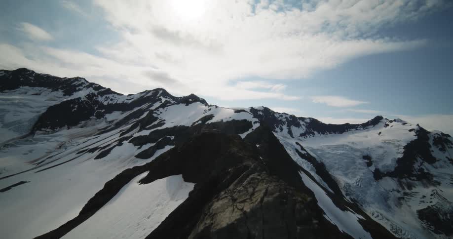 A snow capped mountain ridge under the daytime sky