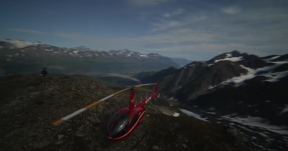 Aerial view of a red helicopter parked on the peak of a mountain