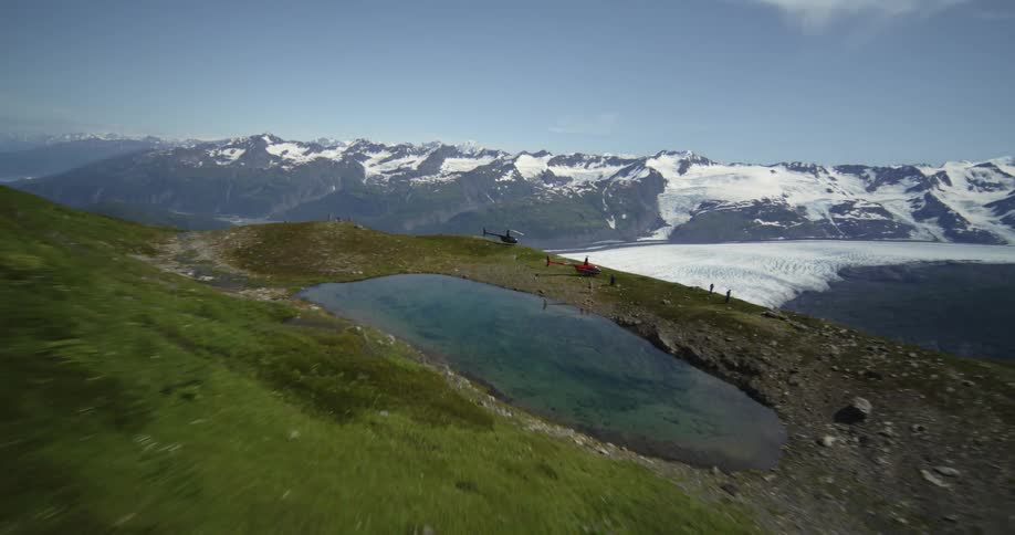View of a mountain range with ice lakes cliffs with people and a helicopter