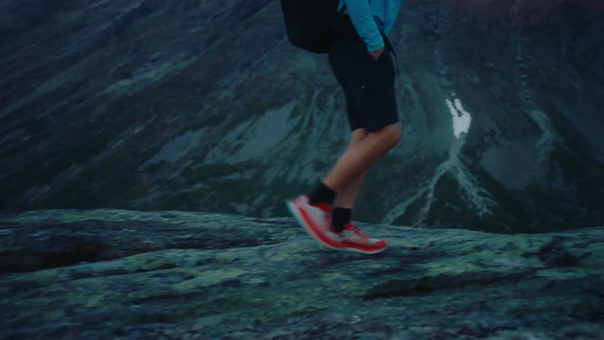 A man on a hiking trail in the mountain while carrying a backpack