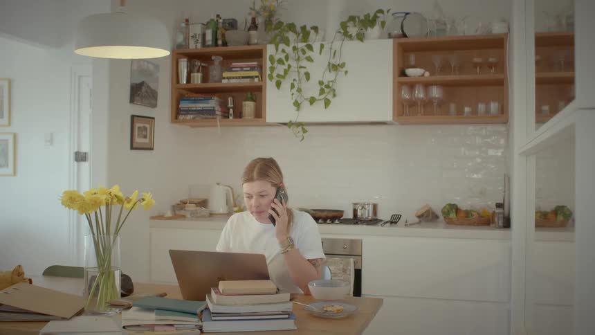 A young woman on call working on the computer at home