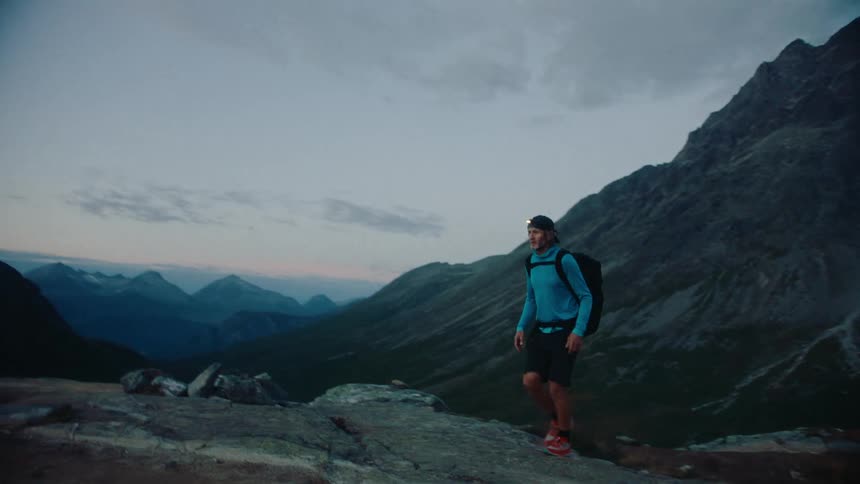 Man carrying a backpack hikes on the mountains at morning