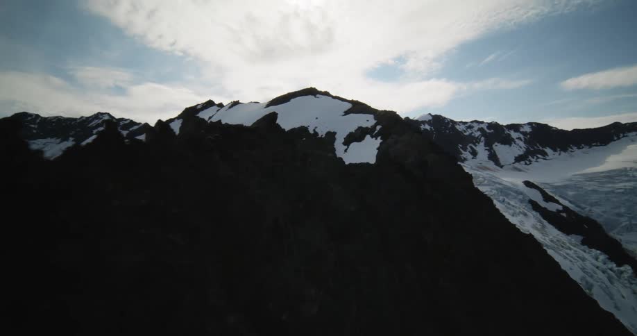 Snow covers a mountain ridge under a cloudy sky