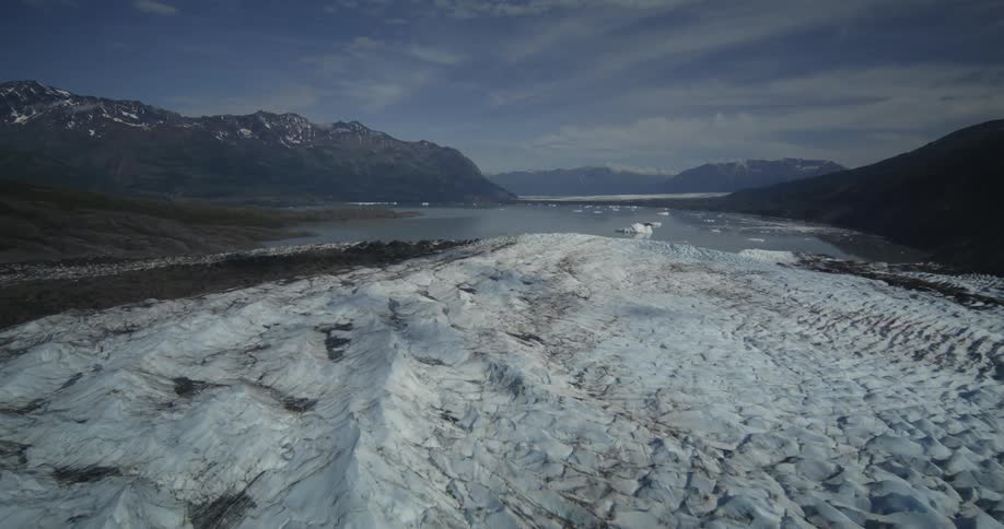 A natural regional landscape with snow on the shore of a lake and mountains in the background