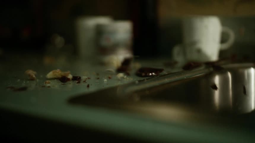 A piece of glassware falls and breaks against a kitchen counter top
