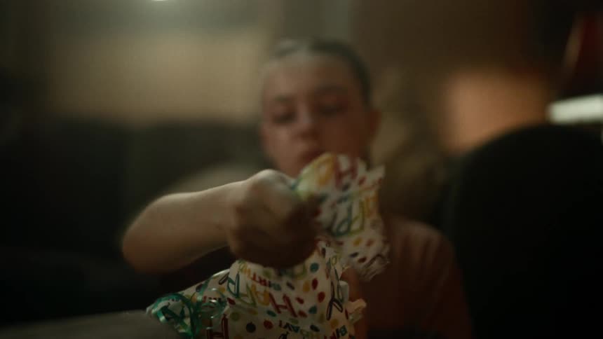 Girl with ponytail and brown t shirt unwraps gift