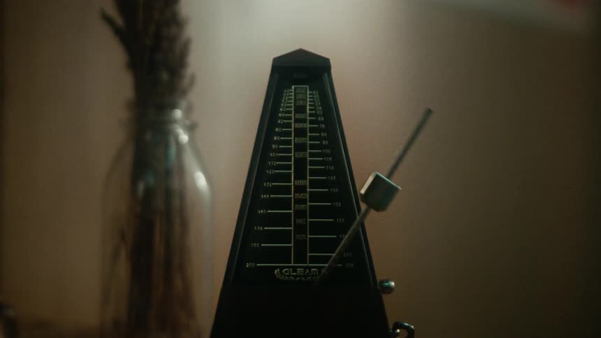Close up of a metronome swinging over a table