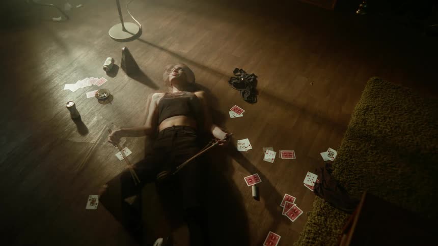 Woman lying on the floor with cards and drinks around her