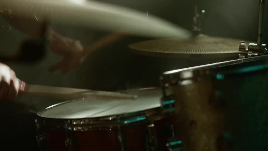 A person playing the drums in a dark room