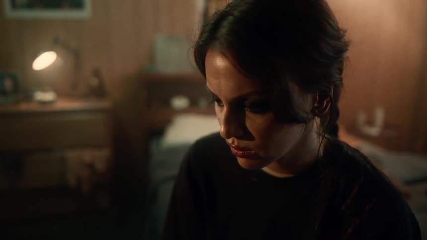 Sad woman with braids and a black shirt stands in a room crying