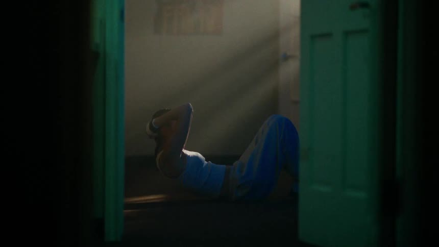 View through a doorway of a woman lying on the floor doing sit ups