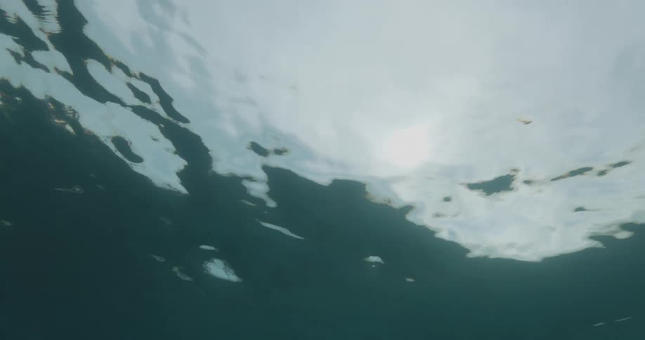 View from inside the sea of water in ripples with the sun reflecting