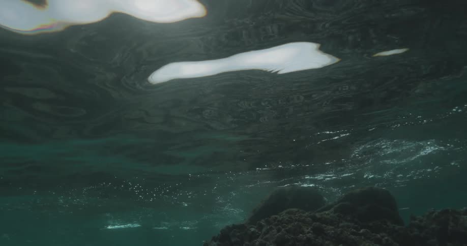 View from inside the sea of moving water with small ripples and a submerged rock ahead