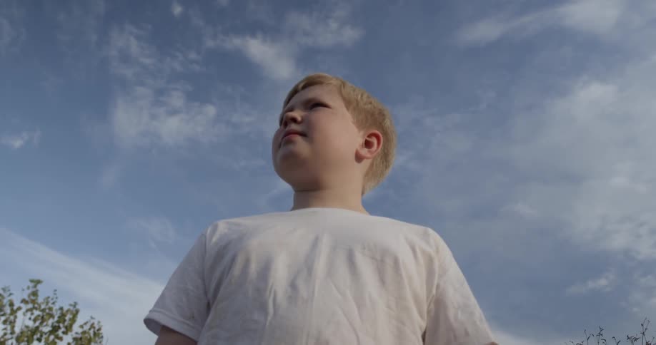 A boy is standing outside on a cloudy day