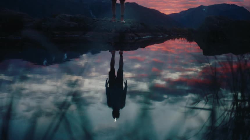Shadow of a person by a natural lake with a reddish sky
