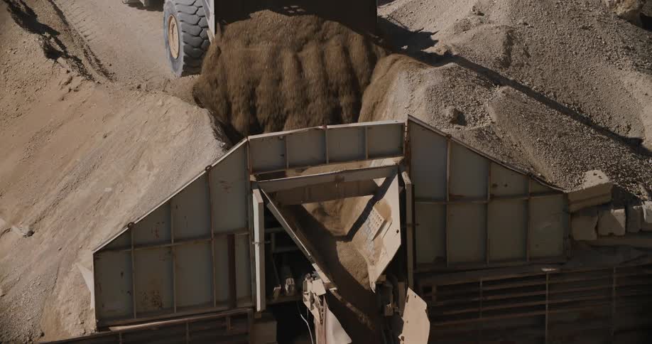 A truck dumping dirt into an industrial machine