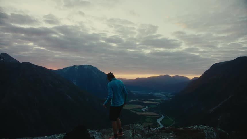 A man on top of a mountain overlooking the valley below