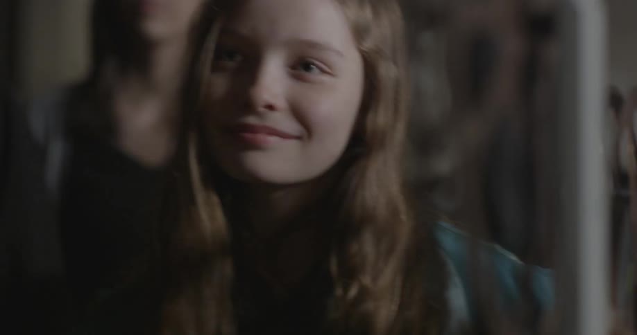 A girl turns to her sides then walks forward by a projector