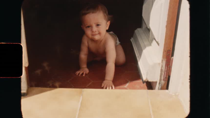 Super 8 film footage of a baby crawling on the floor during the sunny morning