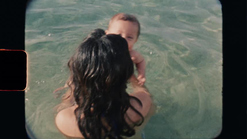Super 8 film of a mother teaching her baby to swim in the sea