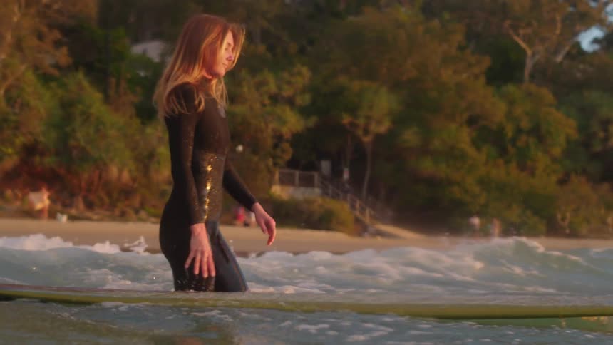 Beautiful young women entering the ocean at sunset