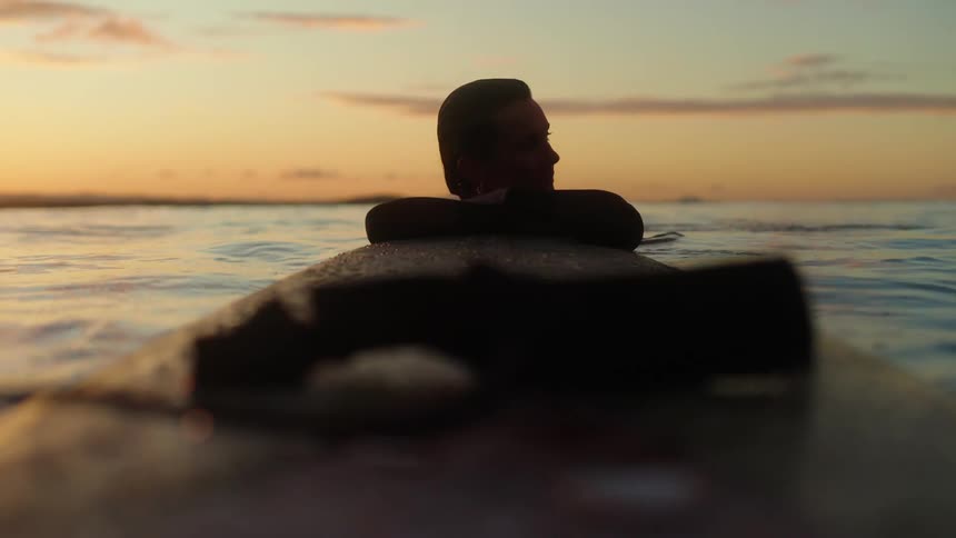 A woman swimming in the ocean holding on to a row boat