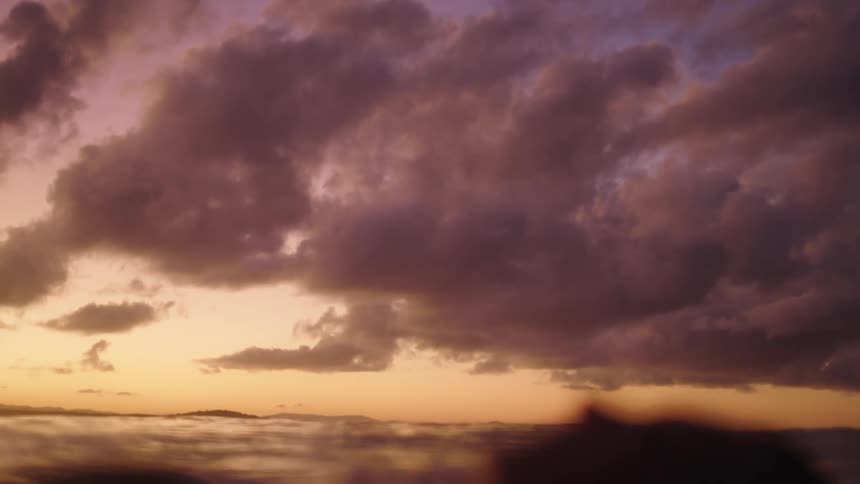The face of a woman floating in the open sea with a reddish sky