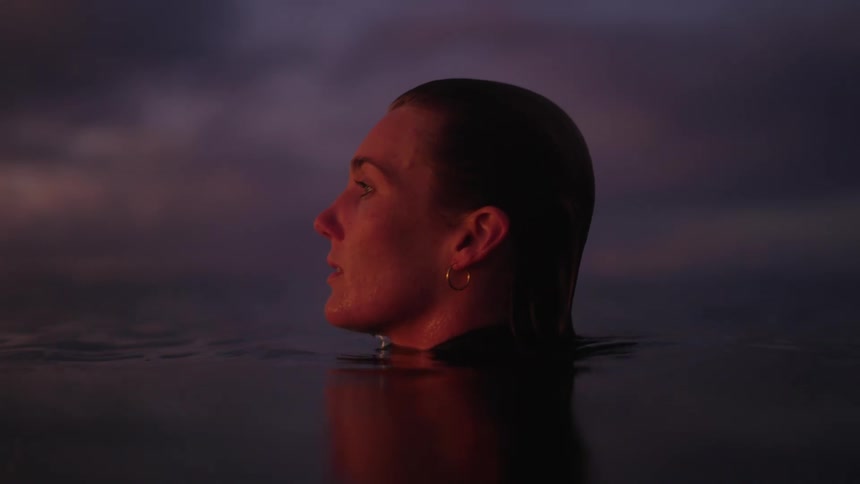 A close up side profile of a womans face as as swims in water looking off into the distance