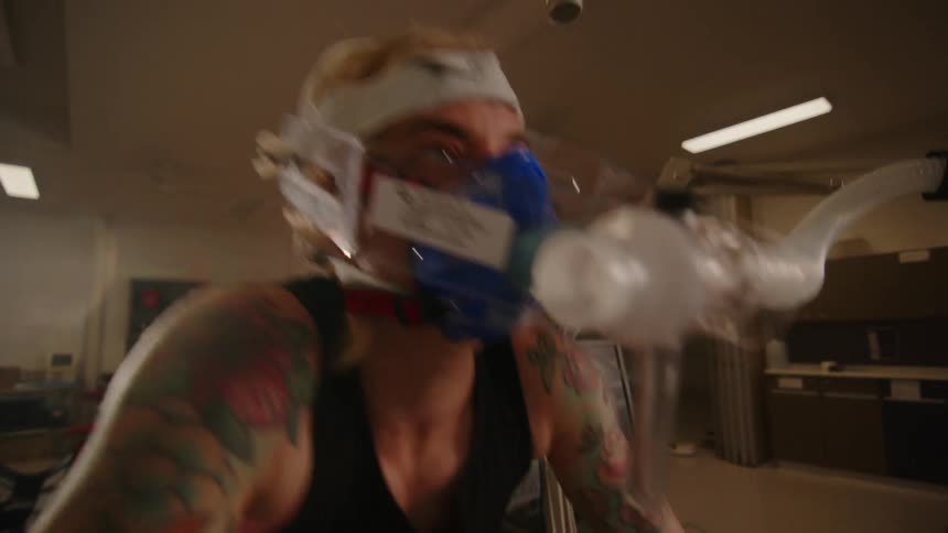 A woman cycling quickly while wearing an oxygen mask