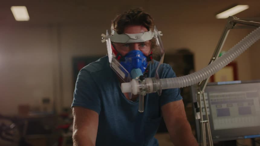 Man performing aerobic test while cycling with a mask covering his mouth and nose