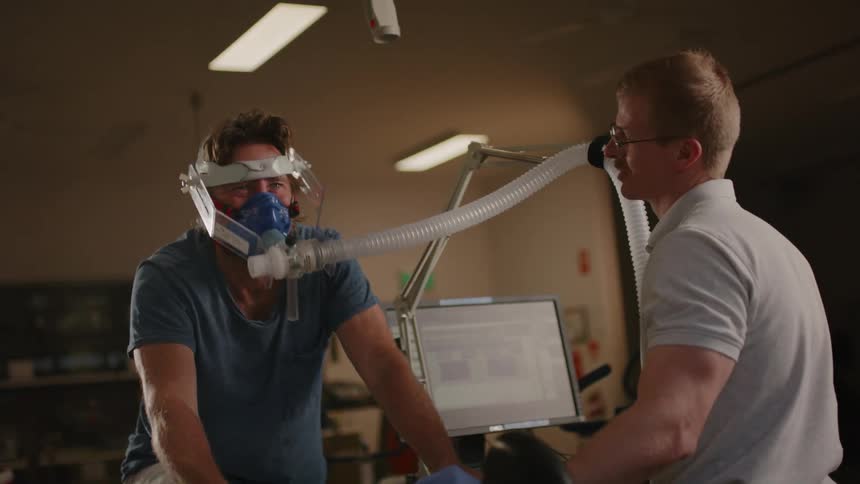 Male technician stands and talks while another man takes a vo2 test