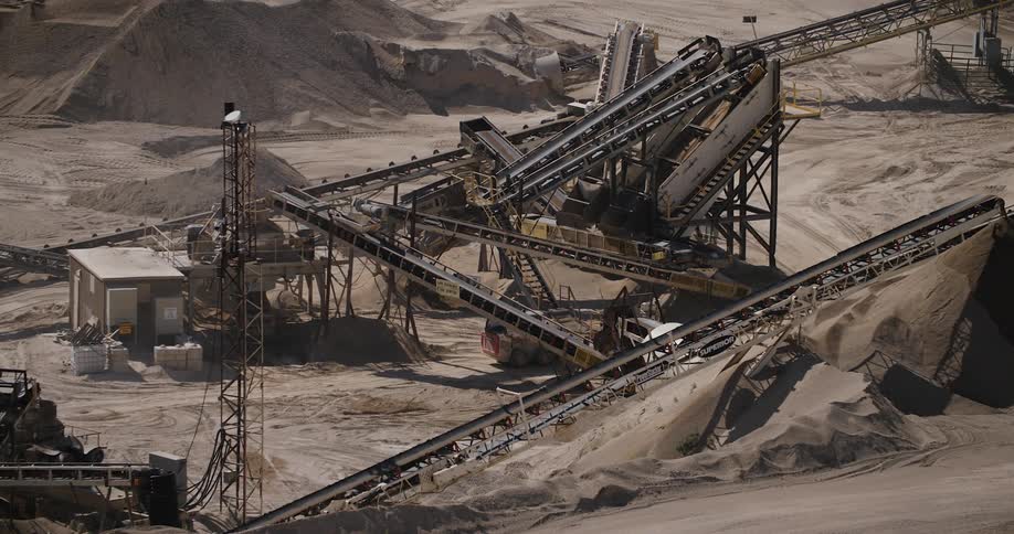 A tractor passing under some machinery in the middle of the desert