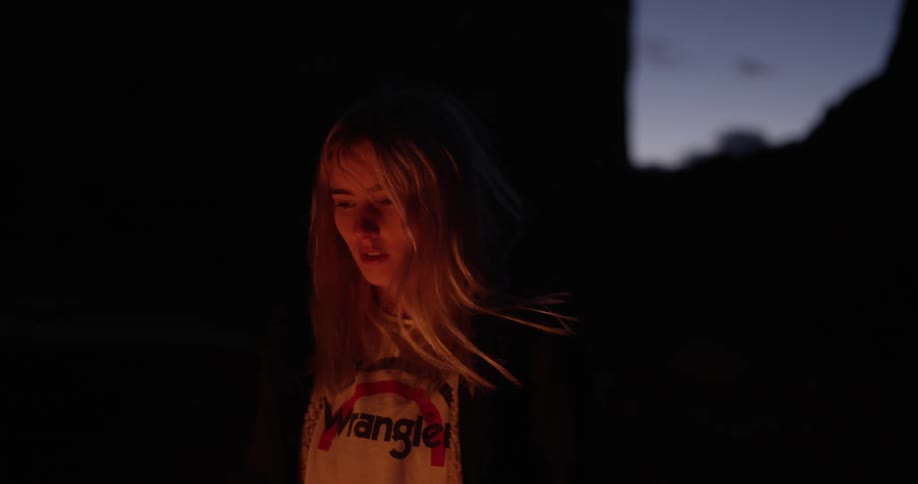 Blonde woman looking into a campfire