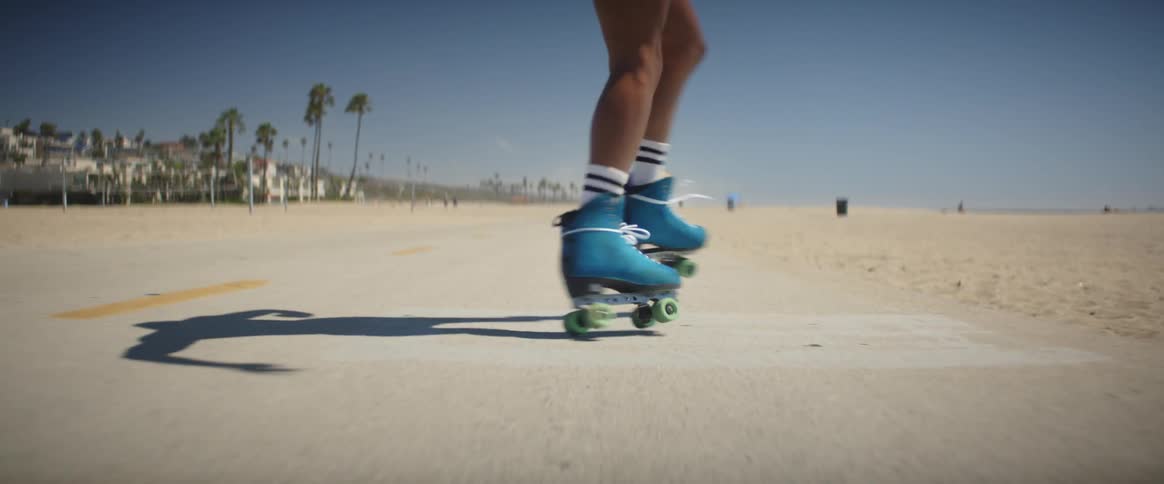Legs of a person roller skating on the sidewalk by the beach