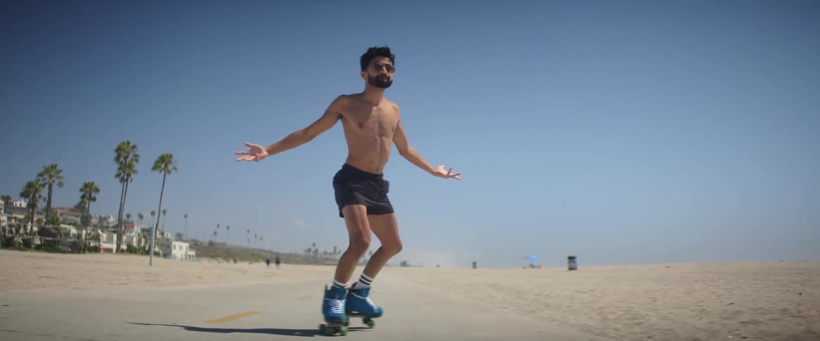Young man on a skating shoe dancing near the beach at midday