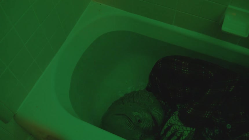 Person wearing a mask covering their face and immersing their body and head in bath water
