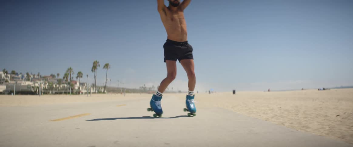 A man is skating by the shore and spinning